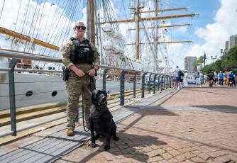U.S. Coast Guard Petty Officer 1st Class Victoria Blandford, a maritime enforcement specialist assigned to the Maritime Safety and Security Team Kings Bay, posed for a photo with K-9 Lea during a pier patrol in the French Quarter in support of Sail 250 New Orleans on May 27.