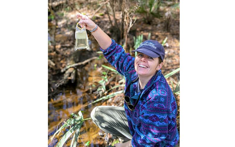 St. Mary’s Riverkeeper Anna Laws shows off the clarity of the water at Horsepen Creek. (Photo by Kendra Shafer)