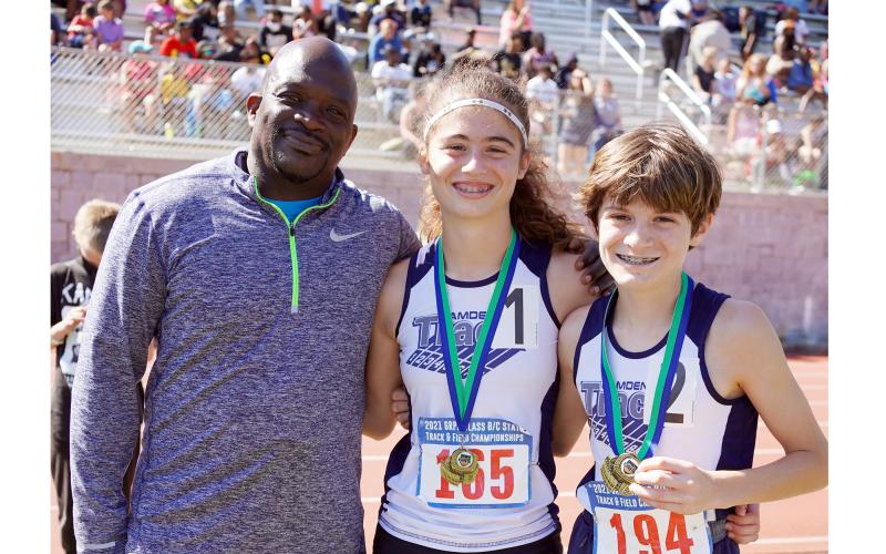 Coach Kerry Jackson stands with Marin Bograd and Asher Bograd, the boys and girls 3200m champions.