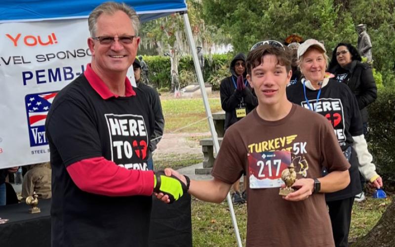Reiley English, shown with race coordinator Brian Andersen, was the first to cross the finish line with a time of 18:30.