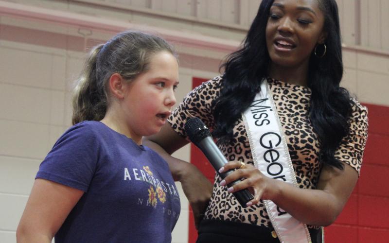 Miss Georgia Kelsey Hollis, right, sings the national anthem Tuesday with Sugarmill Elementary School student Laney Bouley.
