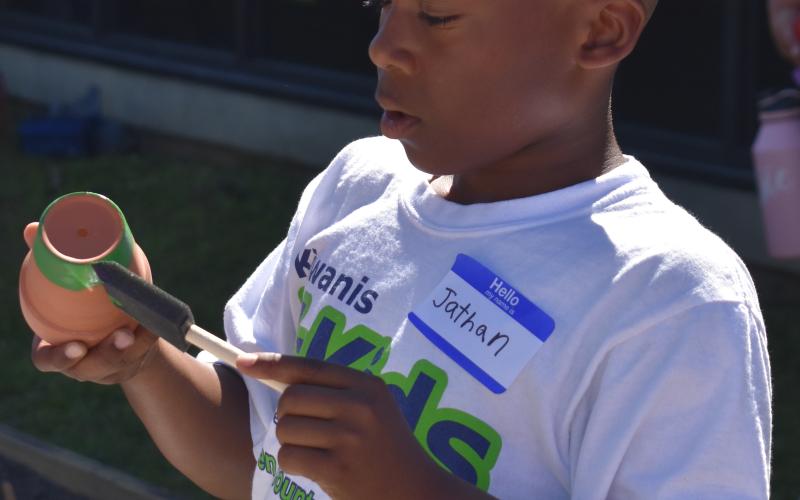 Jathan Simmons paints a small pot at the St. Marys Public Library’s unveiling of its new community garden.