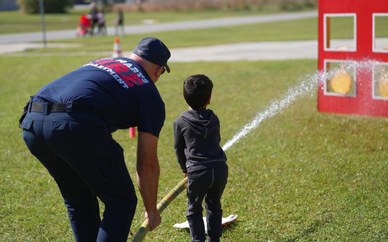 Fire Driver Engineer Matt Rupert shows an open house attendee how to use a fire hose.