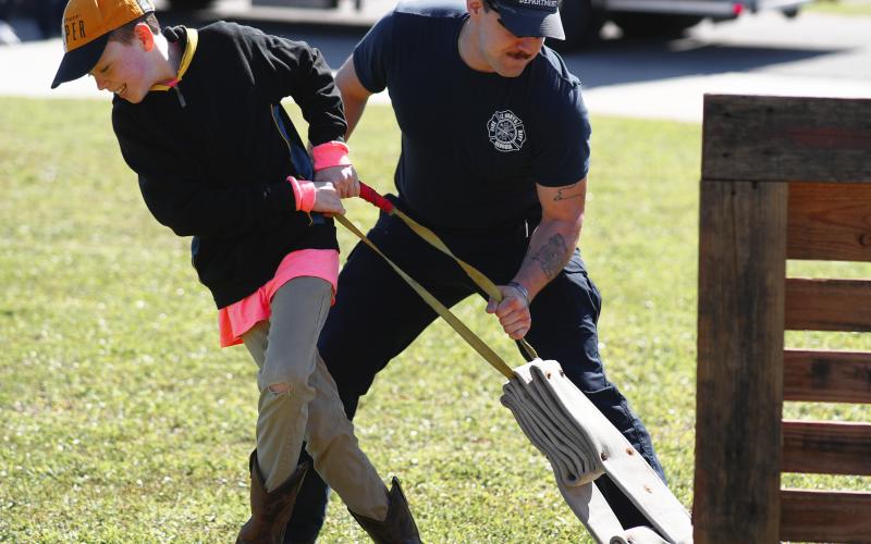 Firefighter Anthony DeMaio shows a young attendee how to unfurl a fire hose.