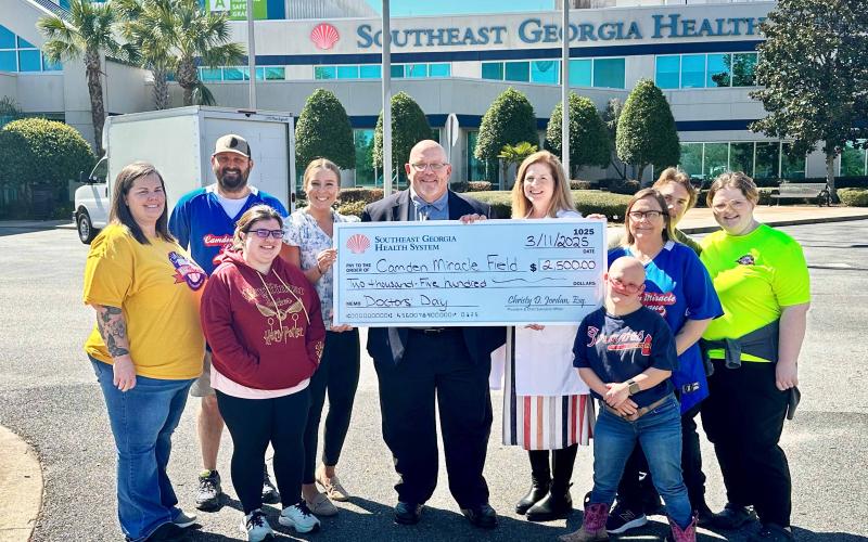 Camden Miracle Field representatives Amy Thompson, board member; Dillon Lacoste, board president; Madison Zapf, board member; Trish Fredricks, board treasurer; volunteer buddies, Ian Fredericks and Keni Hillard; and players, Americas Thompson and  Lisse “The Entertainer” Nettles with Southeast Georgia Health System Camden Campus Vice President and Administrator Glenn Gann and Camden Campus Medical Staff Chief Dr. Janise H. Whitesell celebrate a charitable donation.