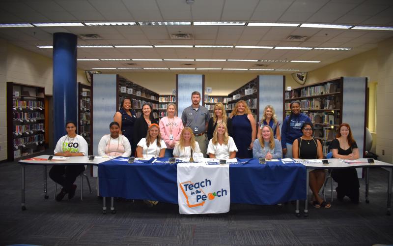 Eight Camden County High School seniors participated in the first-ever Teach in the Peach signing day May 6. Front row, from left, are Nikayla Campbell, Carmella Hutsell, Riley Copeland, Olivia Farrell, Claire McCullough, Lacey Mize, Akeelah Sawehinmi and Elie-Marie Turner. Back row: Sheri Pearson, Erika Smith, Stacie Faulk, James Phillips, Lisa Gleason, Heather Fitzwater, Tara Carter and Sharnesha Smith.