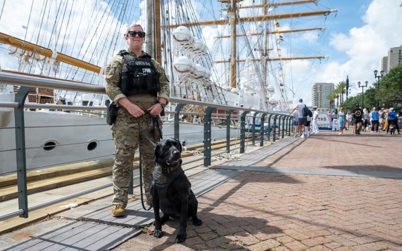 U.S. Coast Guard Petty Officer 1st Class Victoria Blandford, a maritime enforcement specialist assigned to the Maritime Safety and Security Team Kings Bay, posed for a photo with K-9 Lea during a pier patrol in the French Quarter in support of Sail 250 New Orleans on May 27.