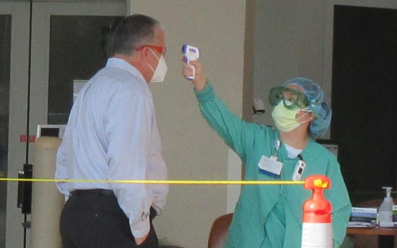 Baptist Medical Center Nassau President Ed Hubel demonstrates how patients, staff, vendors, and anyone else entering the hospital are screened, which includes taking their temperature. JULIA ROBERTS/NEWS-LEADER