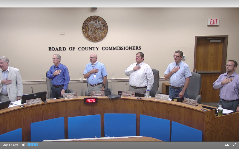 The members of the Nassau County Board of County Commissioners and County Manager and Attorney Mike Mullin stand at attention Wednesday during the Pledge of Allegiance. PEG DAVIS/NEWS-LEADER