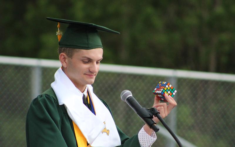 Valedictorian Haden Cottrell holds up a Rubik’s cube to describe students’ future challenges in college.