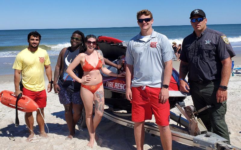 Fernandina Beach Fire Chief Ty Silcox looks on as two kayakers raise their arms in the air after returning to shore Friday, the day Nassau County beaches reopened to the public. Ocean Rescue Lifeguard Spencer Cutajar, seen in the water with a flotation device, along with Ocean Rescue Supervisor Haynes Cavender and NCSO Deputy Garth Holton responded to calls that the kayakers were in trouble. TERRY EBERLE/SPECIAL TO THE NEWS-LEADER