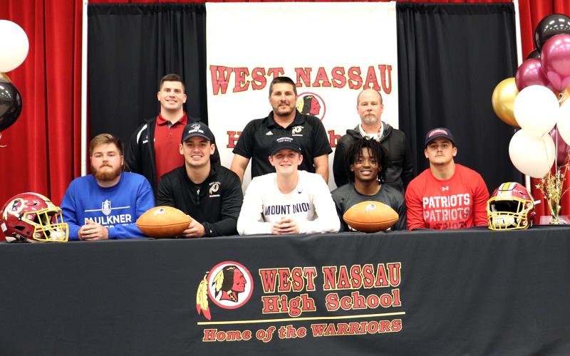 West Nassau football coaches join, from left,  Bryce Morris, Elijah  Canode, Chaz Hirschman,  Zorian Stanton and Bry-son Williams at their college signing celebration Feb. 26.
