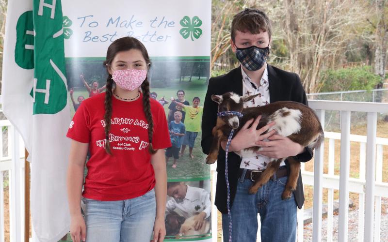 Nassau County 4-H member Garrett Bennett, 12, of Yulee receives a Nigerian dwarf dairy goat Feb. 9 that was born on the family farm of Bryceville’s Sayde Price, 11. 