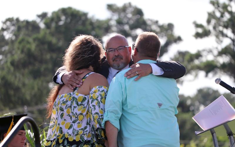 Curtis Gaus hugs the parents of the late Joey Michael Rhoden, Jr. as he presents them with an honorary diploma during graduation June 23. It was Gaus’ eighth and final graduation as principal of West Nassau High School.