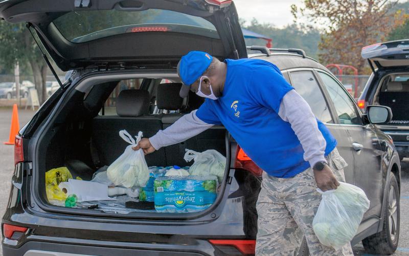 A volunteer places groceries into a vehicle at a recent food distribution. The drive-thru events are held throughout Nassau.