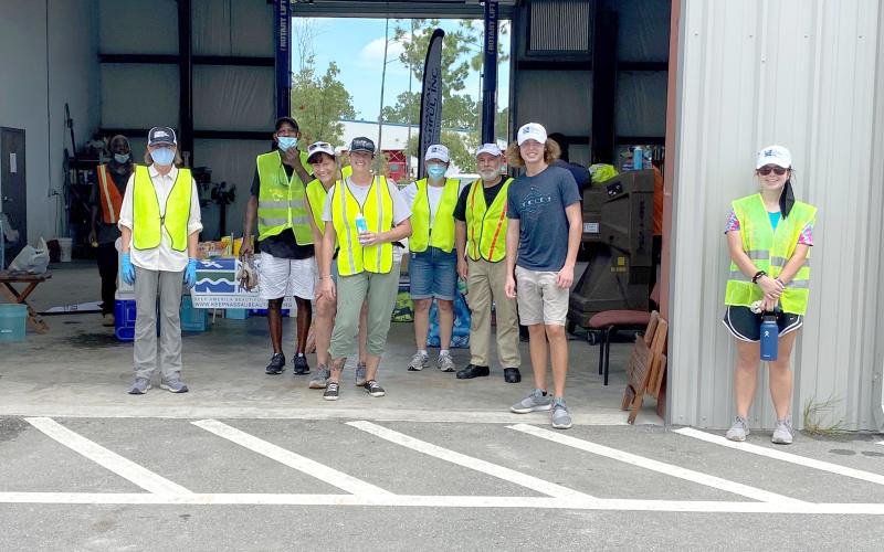 Keep Nassau Beautiful staff and volunteers gather in the shade. They collected hazardous waste from 538 residents Aug. 15. The residents who participated also donated a total of half a ton of non-perishable food items for the Barnabas Food Pantry.