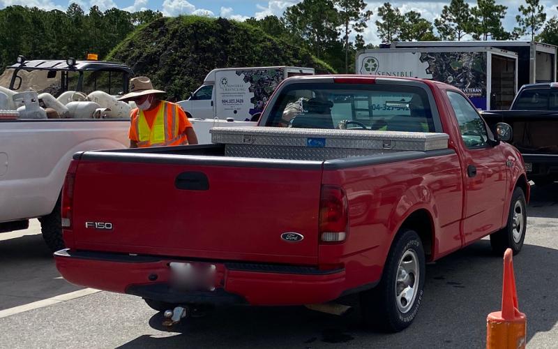 A Nassau County worker wearing a mask over his mouth, but not over his nose, helps citizens unload their vehicles at a recent recycling event. PEG DAVIS/NEWS-LEADER