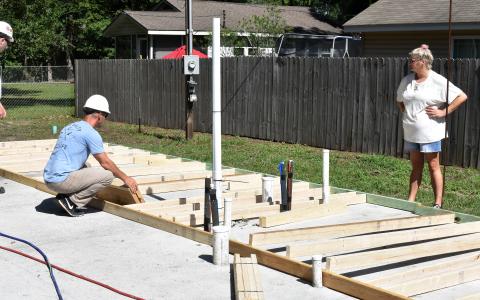 Taylor Tyson watches Lockheed Martin volunteers layout the framing for her Habitat house.