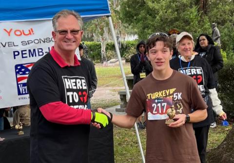 Reiley English, shown with race coordinator Brian Andersen, was the first to cross the finish line with a time of 18:30. 
