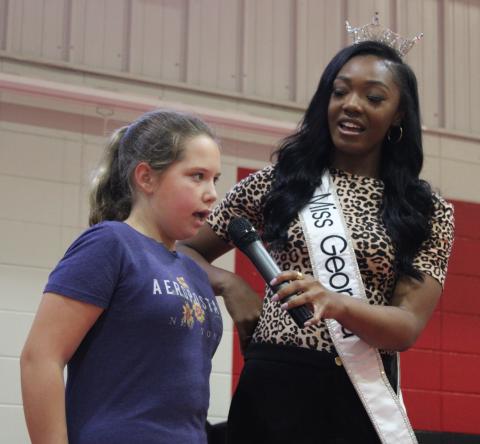 Miss Georgia Kelsey Hollis, right, sings the national anthem Tuesday with Sugarmill Elementary School student Laney Bouley.