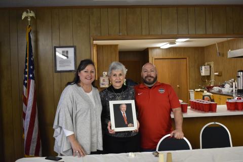 Suzanne M. Johnson, Mary McCollum and Butch Livingstone hold up a photo of Jimmy McCollum, for whom the American Legion Post 170 was named after during a ceremony Saturday.