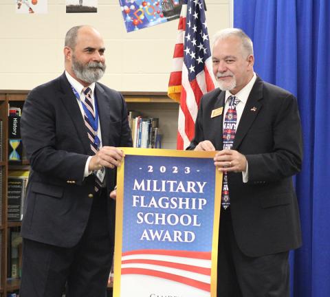 Camden Middle School Principal Heath Heron, left, accepts the Military Flagship School Award banner from Georgia State Superintendent Richard Woods.