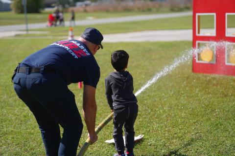 Fire Driver Engineer Matt Rupert shows an open house attendee how to use a fire hose.