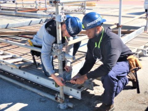 Two Kings Bay Trident Refit Facility apprentices work to set up scaffolding to support repair work on submarines.