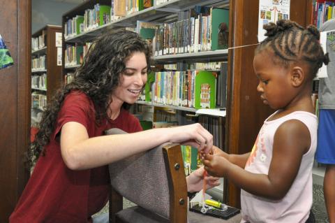 Evelyn Ashe, a Strategic Weapons Facility, Atlantic (SWFLANT) engineering student intern, helps a child prepare her straw missile for launch June 28 at the Camden County Public Library in Kingsland. A team of volunteers from SWFLANT, Lockheed Martin and General Dynamics hosted the event during the Science, Technology, Engineering and Mathematics (STEM) day of the library’s summer learning series. 