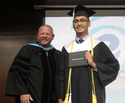 Coastal Plains High School graduate Jayden Hardy, right, shows off his diploma holder with site director Derek Chastain on Thursday night during the program’s commencement exercises at Camden County High School.
