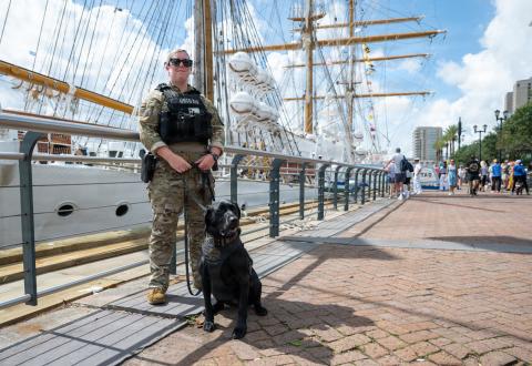 U.S. Coast Guard Petty Officer 1st Class Victoria Blandford, a maritime enforcement specialist assigned to the Maritime Safety and Security Team Kings Bay, posed for a photo with K-9 Lea during a pier patrol in the French Quarter in support of Sail 250 New Orleans on May 27.