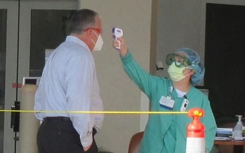 Baptist Medical Center Nassau President Ed Hubel demonstrates how patients, staff, vendors, and anyone else entering the hospital are screened, which includes taking their temperature. JULIA ROBERTS/NEWS-LEADER