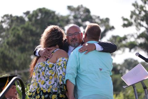 Curtis Gaus hugs the parents of the late Joey Michael Rhoden, Jr. as he presents them with an honorary diploma during graduation June 23. It was Gaus’ eighth and final graduation as principal of West Nassau High School. 