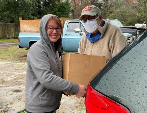 Barnabas volunteer Robert Simoneau delivers an Amelia Fresh box to a Barnabas client. The Amelia Fresh boxes include a variety of locally produced items.