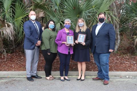 Nassau County Manager Taco Pope, from left, Planning and Economic Opportunity Department Planner/GIS analyst Abby Weiss, Planning and Zoning Board member Linda Morris, Northeast Florida Regional Planning CEO Beth Payne and Nassau County Board of County Commissioners Chairman Thomas Ford pose with the two leadership awards the county received.