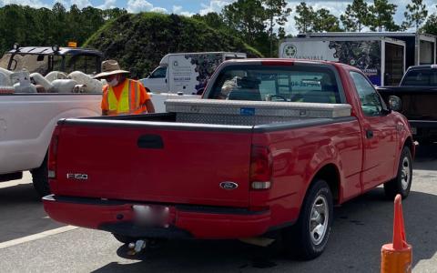 A Nassau County worker wearing a mask over his mouth, but not over his nose, helps citizens unload their vehicles at a recent recycling event. PEG DAVIS/NEWS-LEADER
