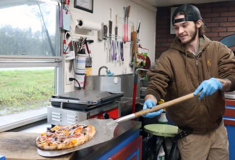 Krusty Kraken’s Austin Downing prepares to box an oven-baked pizza. 