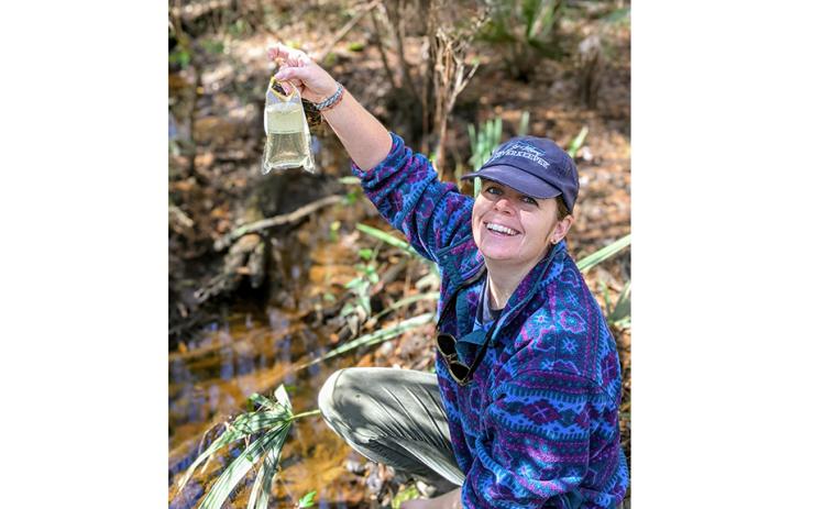 St. Mary’s Riverkeeper Anna Laws shows off the clarity of the water at Horsepen Creek. (Photo by Kendra Shafer)
