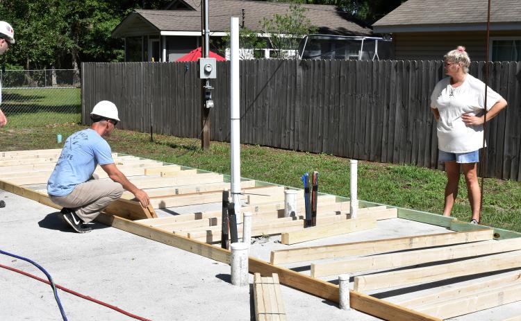 Taylor Tyson watches Lockheed Martin volunteers layout the framing for her Habitat house.