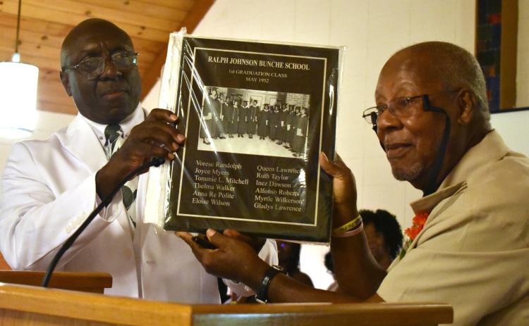 Tommie Mitchell, right, a member of the Ralph Johnson Bunche High School class of 1952, presents a plaque of the graduating class to Artie Jones, president of the high school and Camden County Training School alumni association.