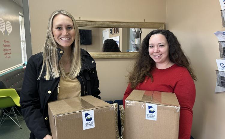 Georgia Cotton Commission Education and Outreach Specialist Caroline Gentry, left, presents Safe Harbor Children Advocacy Center’s Brionna Jones with 125 pairs of socks on behalf of the state’s 3,000 cotton farmers.