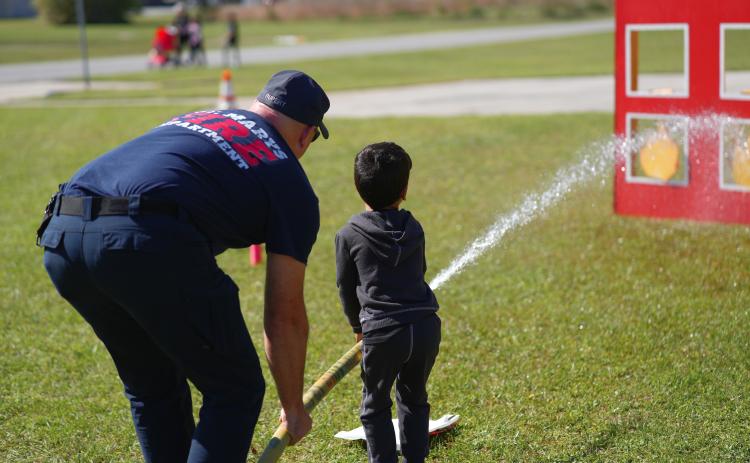 Fire Driver Engineer Matt Rupert shows an open house attendee how to use a fire hose.