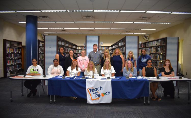Eight Camden County High School seniors participated in the first-ever Teach in the Peach signing day May 6. Front row, from left, are Nikayla Campbell, Carmella Hutsell, Riley Copeland, Olivia Farrell, Claire McCullough, Lacey Mize, Akeelah Sawehinmi and Elie-Marie Turner. Back row: Sheri Pearson, Erika Smith, Stacie Faulk, James Phillips, Lisa Gleason, Heather Fitzwater, Tara Carter and Sharnesha Smith.