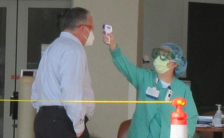Baptist Medical Center Nassau President Ed Hubel demonstrates how patients, staff, vendors, and anyone else entering the hospital are screened, which includes taking their temperature. JULIA ROBERTS/NEWS-LEADER
