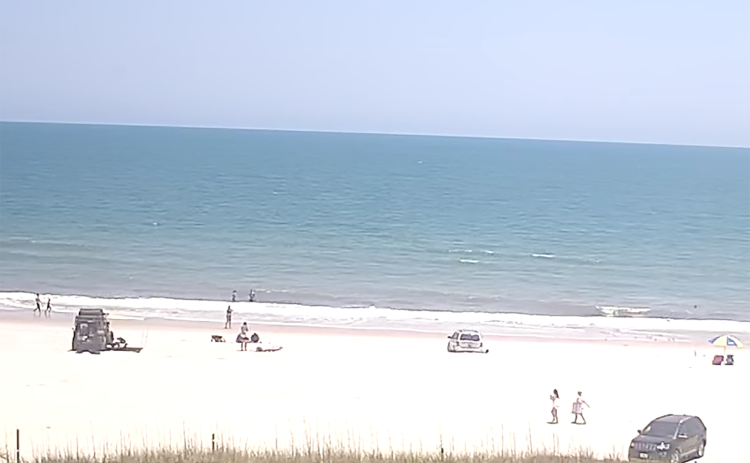 A video of Susan Jakuszewski being run over by a vehicle on the beach behind Sliders Seaside Grill remains online. The video is posted by a user named “Beach Bum” and titled “Live Stream – Sliders Seaside Grill.”