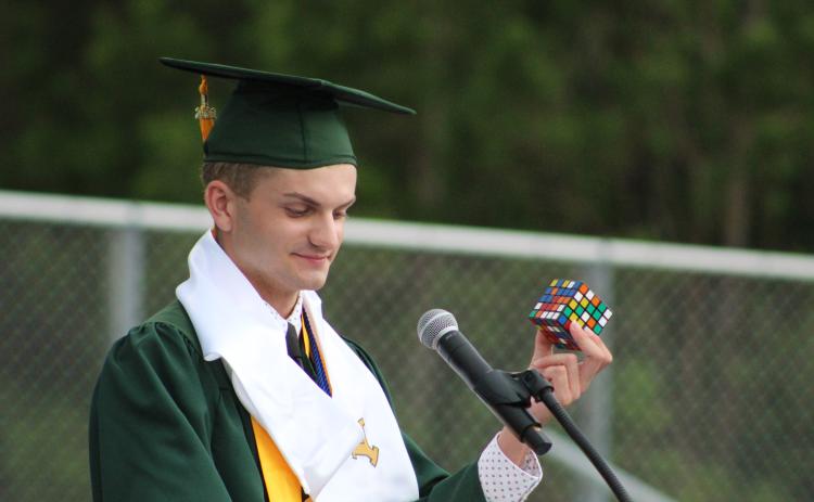Valedictorian Haden Cottrell holds up a Rubik’s cube to describe students’ future challenges in college.