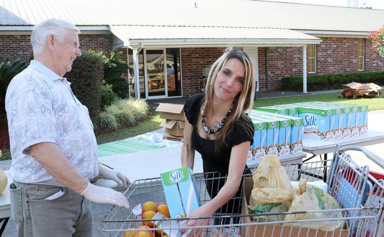 Katie Crane receives items from Gary Norris as residents line up to collect fruit, meat and other goods from a Farm Share food distribution at Hilliard’s Buford Grove Baptist Church March 18.