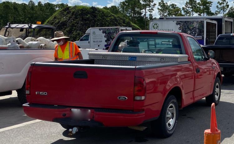 A Nassau County worker wearing a mask over his mouth, but not over his nose, helps citizens unload their vehicles at a recent recycling event. PEG DAVIS/NEWS-LEADER