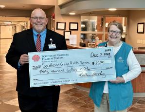 Southeast Georgia Health System Camden Campus Vice President and Administrator Glenn Gann, left, accepts a $30,000 donation from Volunteer Services President Kathleen Worthing.