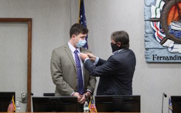 Outgoing Mayor Johnny Miller gives the pin he wore to his last City Commission on Tuesday to Bradley Bean, who won Miller's Group 1 seat. Miller was term-limited from running again. JULIA ROBERTS/NEWS-LEADER